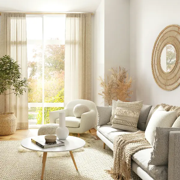 Bright, white living space with a large area rug, blankets and pillows on the couch, giving a very comfy vibe.