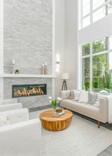 Floor to ceiling fireplace in white and grey living room setting with similar window space and tall ceilings