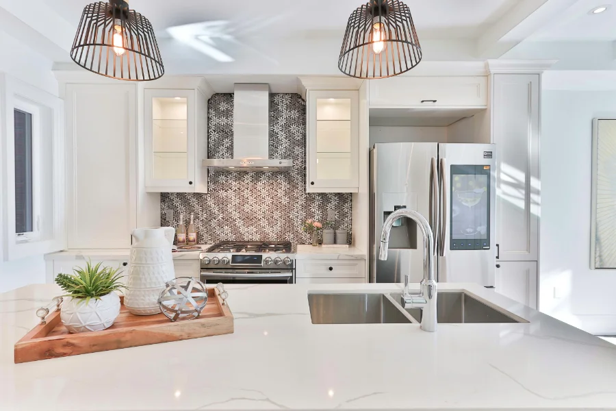 Professionally designed kitchen with floral backsplash tile behind oven range, deep two-part sink, and granite countertops