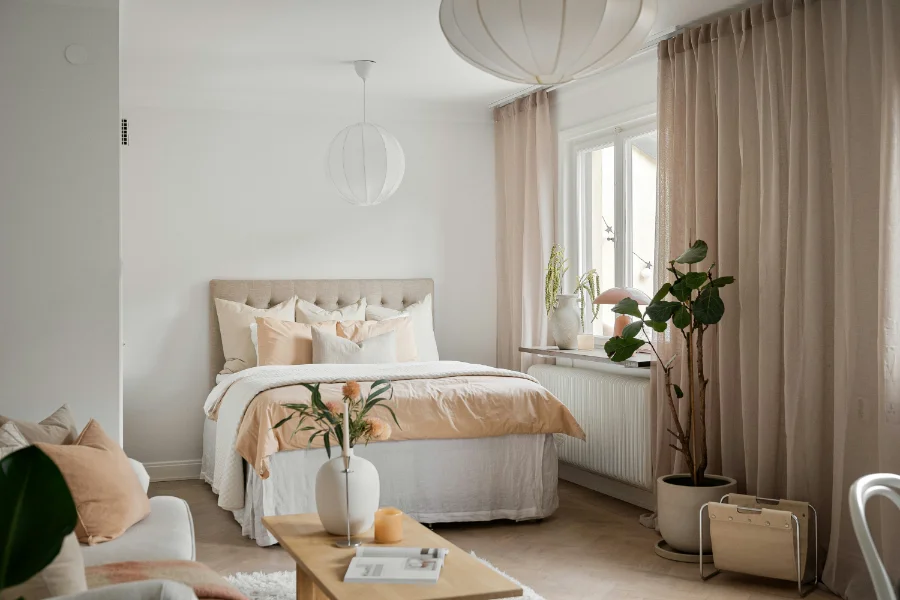 A feminine feeling sleeping space with pale pink accents throughout the white room, with candles and flowers