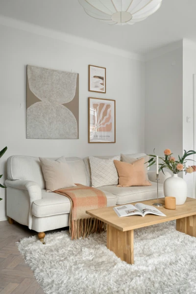 A bedroom sitting space, light couch with rose pink accents, wood coffee table, and shag area rug